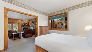 Une chambre à coucher avec un grand lit, une armoire en bois, un bureau, une chaise et une cheminée.