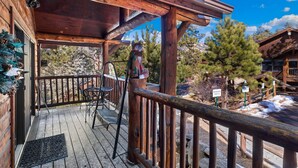 A wooden deck with a railing, a chair, and a table.