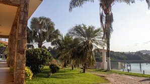 A pathway lined with palm trees and a view of a bridge over water. - Pousada Recanto de Igaratá (Igarata)