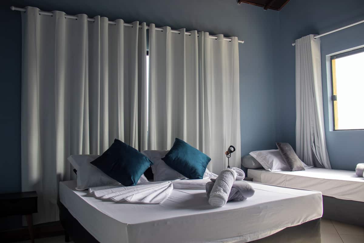Una habitación de hotel con dos camas, ropa de cama blanca y almohadas azules.
