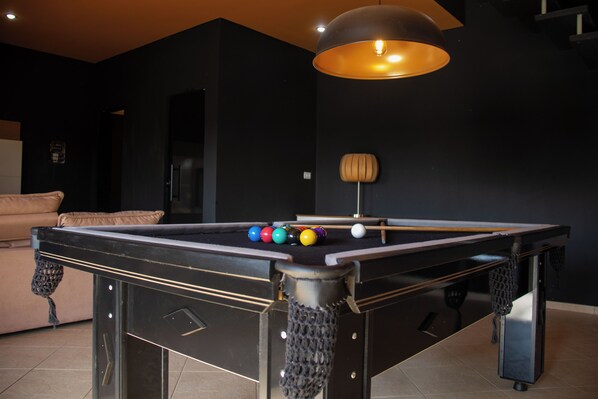 A pool table with balls, a sofa, and a lamp in a room with dark walls. - Pousada Recanto de Igaratá (Igarata)