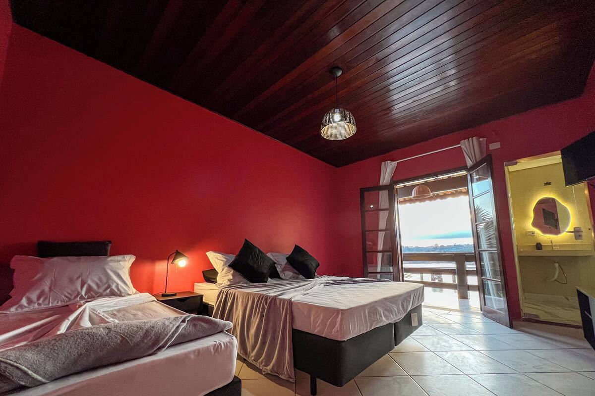 Un dormitorio con dos camas, una mesita de noche, una lámpara, una ventana con vistas y un espejo con luces.