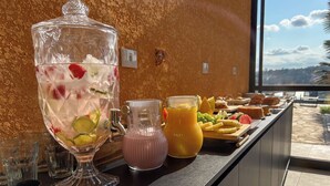 A breakfast bar with a large punch bowl, a pitcher of orange juice, and a variety of pastries and fruits. - Pousada Recanto de Igaratá (Igarata)