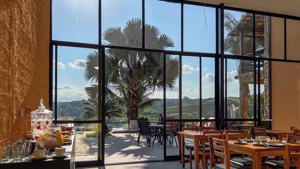 A spacious dining area with large windows offering a view of the countryside. - Pousada Recanto de Igaratá (Igarata)