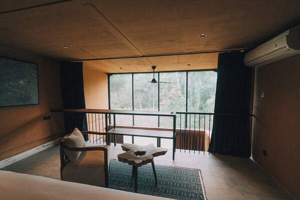 Una habitación moderna con un ventanal grande, un ventilador de techo, un banco de madera y una mesita pequeña.