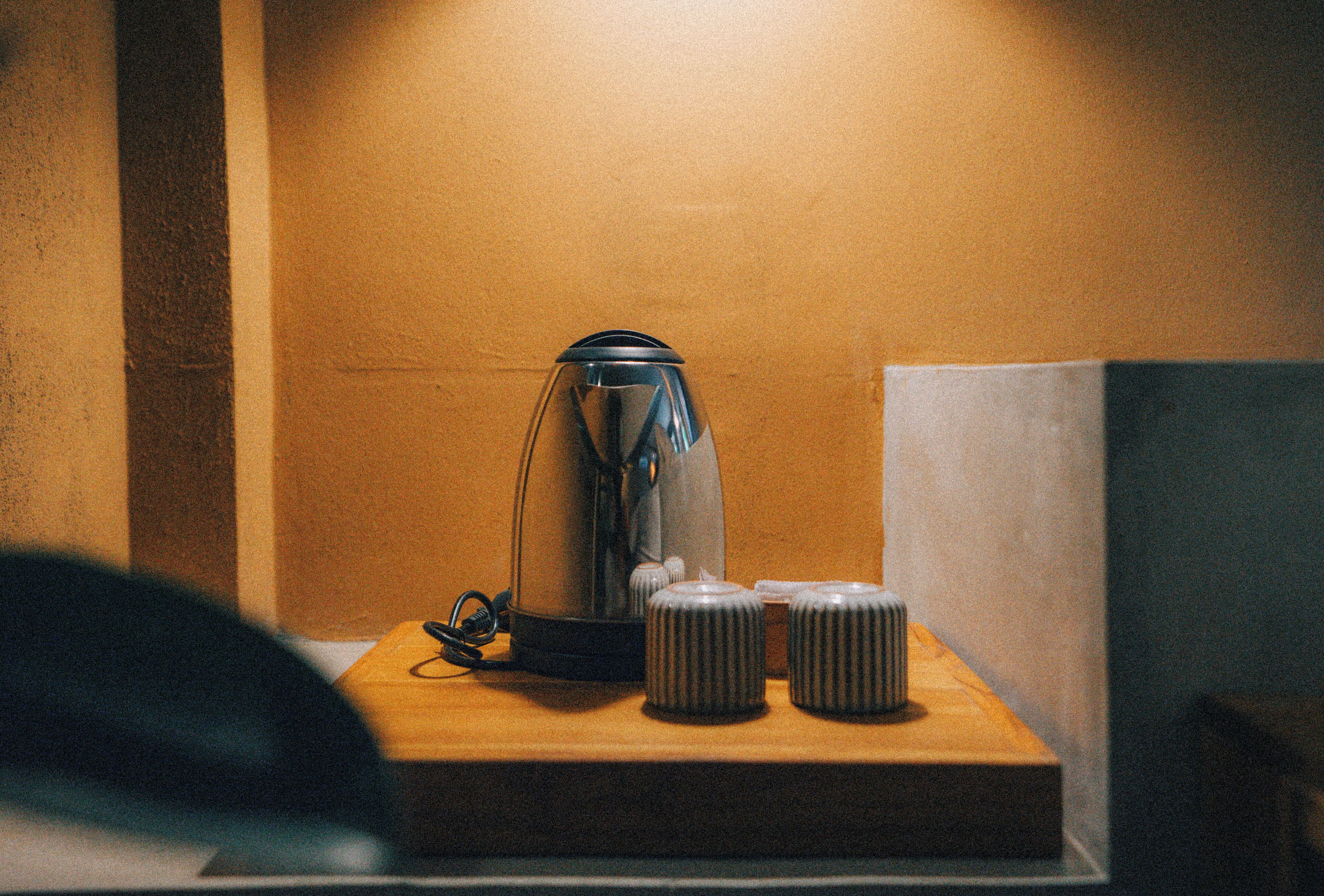 Une machine à café est posée sur une surface en bois, avec deux récipients cylindriques à côté.