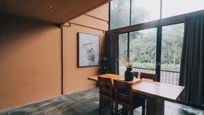 Un coin repas avec une table et des chaises en bois, un vase contenant des plantes séchées et un tableau encadré accroché au mur.