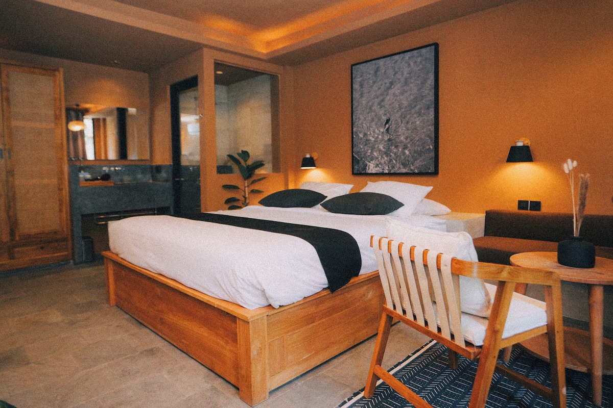 A modern hotel room with a wooden bed, a desk, and a chair.