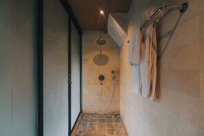 A narrow shower area with a showerhead, a towel rack, and a tiled floor. - Loji Nyanyi Suite & Brew (Cemagi)
