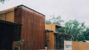 Un bâtiment moderne doté d’une façade verticale en bois, d’un mur en pierre et d’une entrée en béton.