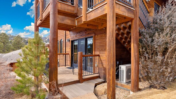 Eine Holzhütte mit einer Terrasse, großen Fenstern und einer Treppe zu einem Balkon.