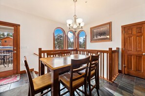 Enjoy meals in this dining area with a large table and comfortable chairs, surrounded by a chandelier and a beautiful view.