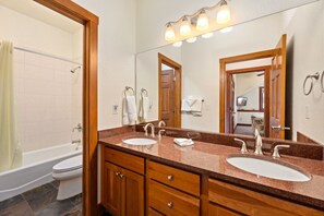 Bathroom features a double sink, large mirror, and a bathtub with shower curtain.