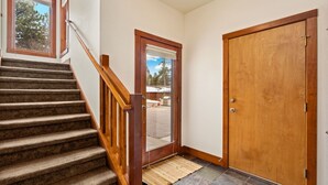 Eine Treppe mit Holzwurf und Geländern, die zu einer Tür mit Fenster darüber führt.