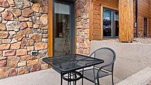Een stenen buitenmuur met een houten deur en een metalen tafel met stoelen voor een gebouw.