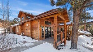 Eine Holzhütte mit überdachter Veranda, großen Fenstern und verschneitem Gelände.