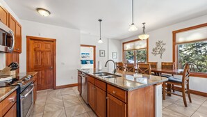 A kitchen with wooden cabinets, a granite countertop, a built-in oven, a sink, and pendant lighting.