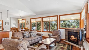 A spacious living room with a fireplace, large windows, and a cozy seating area.