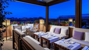 Un área de comedor al aire libre con mesas, sillas, un sofá y plantas en macetas.