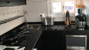 Una cocina moderna con encimeras negras, electrodomésticos de acero inoxidable, una olla en la estufa y una cafetera.