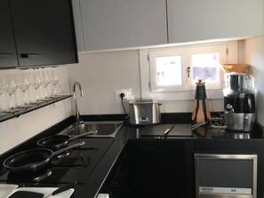 A modern kitchen with black countertops, stainless steel appliances, a pot on the stove, and a coffee maker. - Roof Suite Rome Suitable for 6 Persons (Rome)