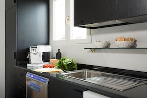 A modern kitchen with black cabinets, a coffee machine, a dishwasher, and a window with natural light. - Roof Suite Rome Suitable for 6 Persons (Rome)