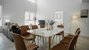 Zona de menjador moderna amb taula de marbre, cadires marrons i una finestra gran que deixa entrar llum natural.