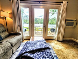 Una stanza con un divano, una coperta e vista su un patio con mobili da esterno e un barbecue.
