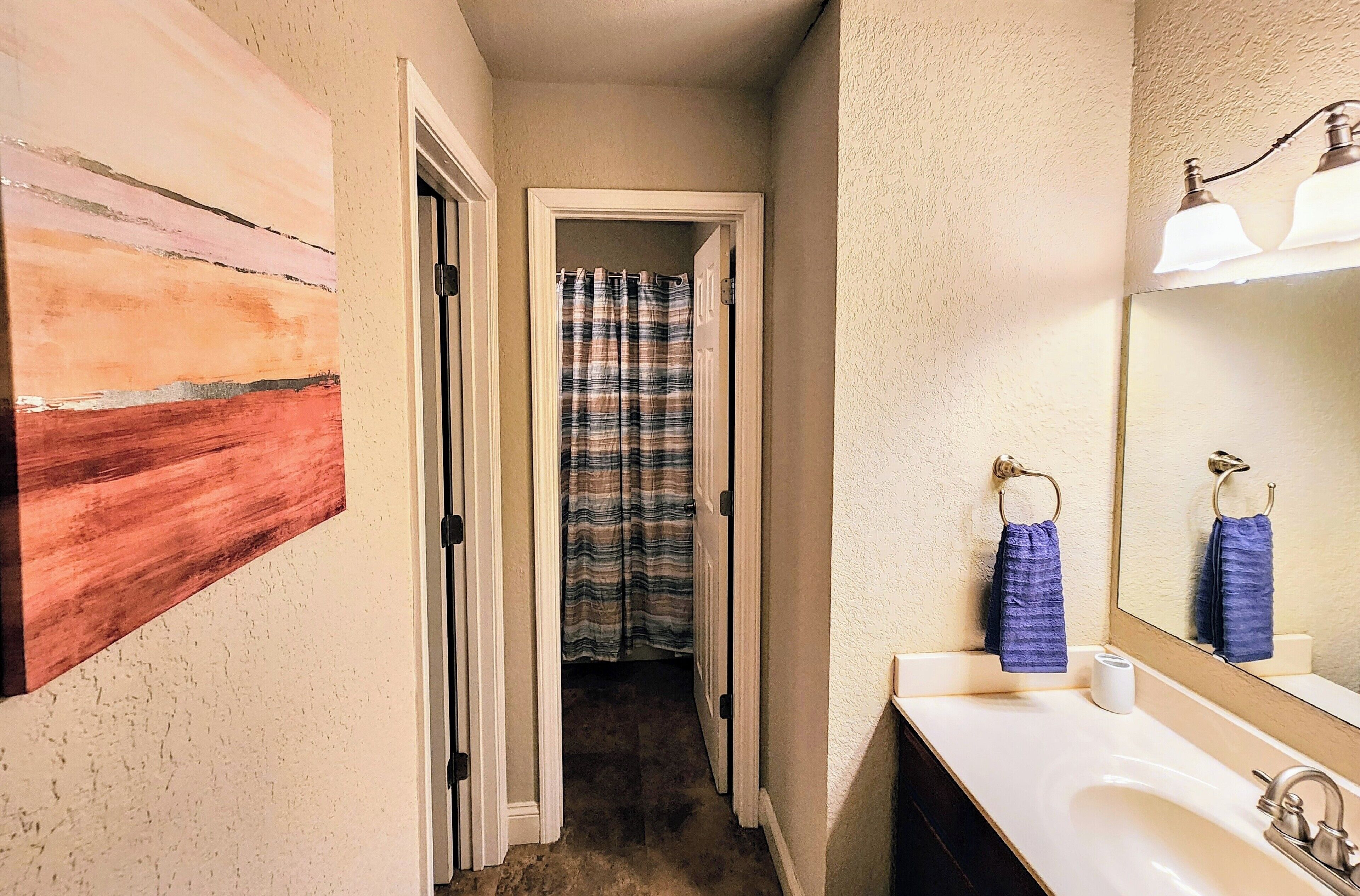 Une salle de bain avec un lavabo blanc, un miroir et un rideau de douche.