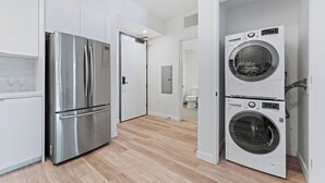 Une cuisine moderne équipée d’un réfrigérateur en acier inoxydable, d’un four double et d’un lave-linge et d’un sèche-linge intégrés.