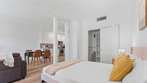 A modern hotel room with a large bed, a sofa, a dining area, and a kitchen in the background. - Stylish Downtown LA Gateway (Los Angeles)