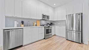 A modern kitchen with stainless steel appliances, white cabinetry, and a wooden countertop. - Stylish Downtown LA Gateway (Los Angeles)