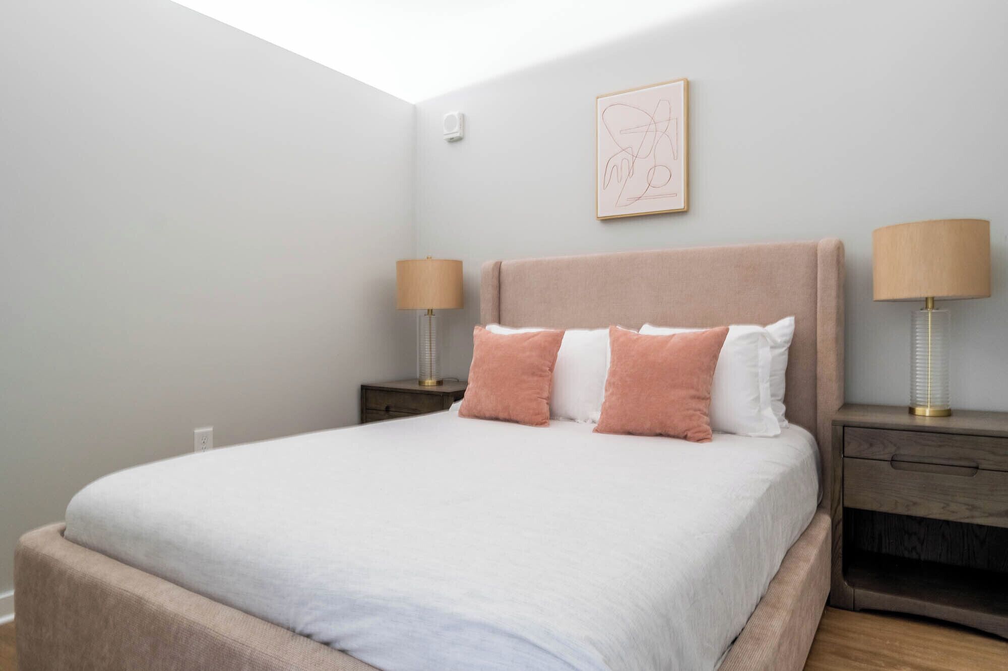 Une chambre à coucher avec un lit, deux tables de chevet et une lampe fixée au mur.