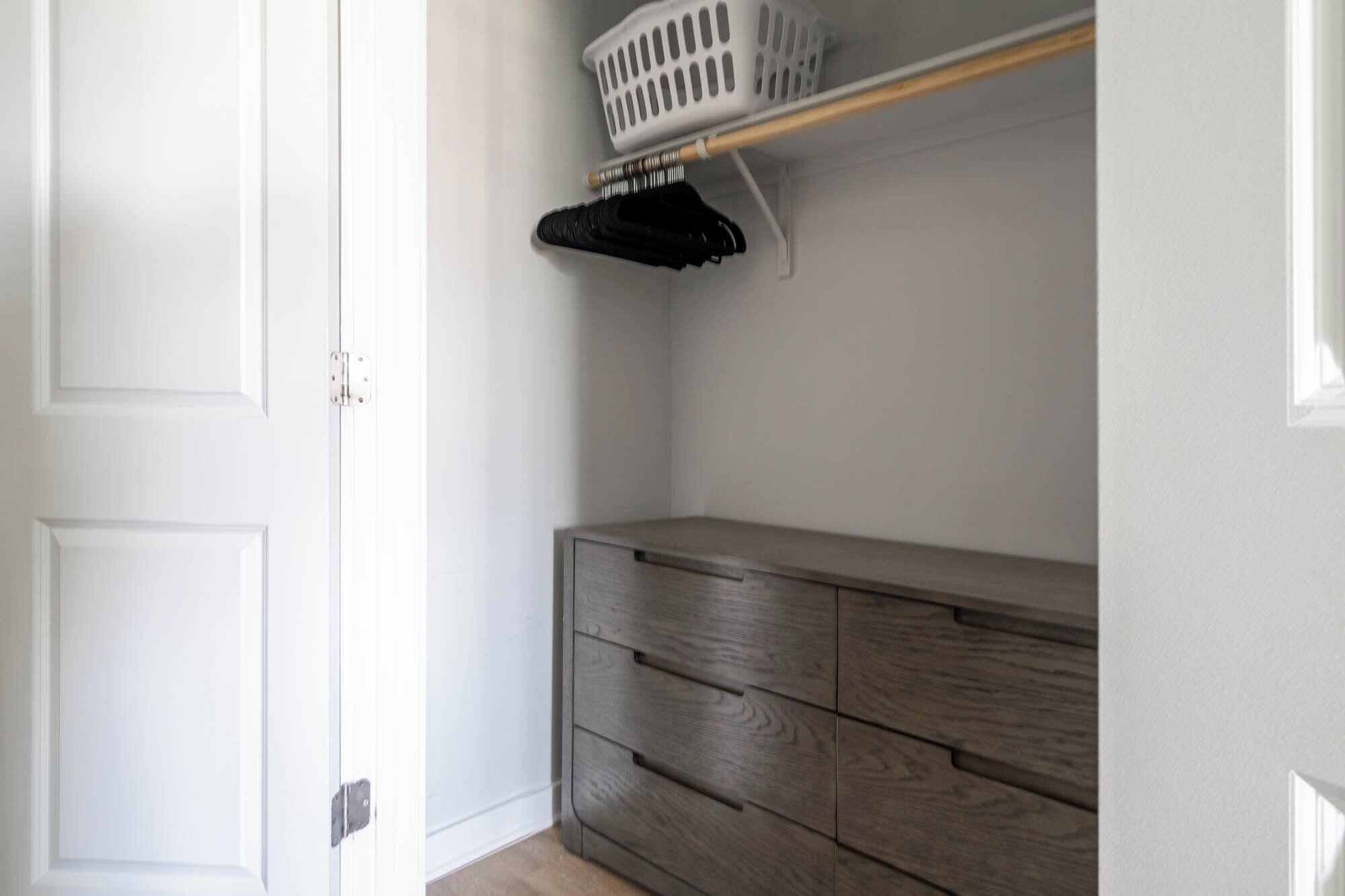 A closet with a wooden dresser and a hanging rack.