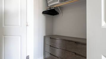 A closet with a wooden dresser and a hanging rack.