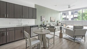 Una cocina moderna con armarios oscuros, salpicadero de azulejos blancos y una zona de comedor con una mesa redonda y sillas.