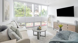 Una sala de estar moderna con un sofá, un sillón, una mesa de centro y un televisor montado en la pared.