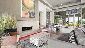 A spacious living room with a fireplace, comfortable seating, and large windows offering a view of the outdoors.