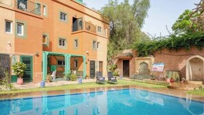 A hotel with a swimming pool, outdoor seating, and a garden area.