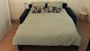Ein Schlafzimmer mit einem Bett, zwei Kissen, einer Hängeleuchte und zwei gerahmten Bildern an der Wand.