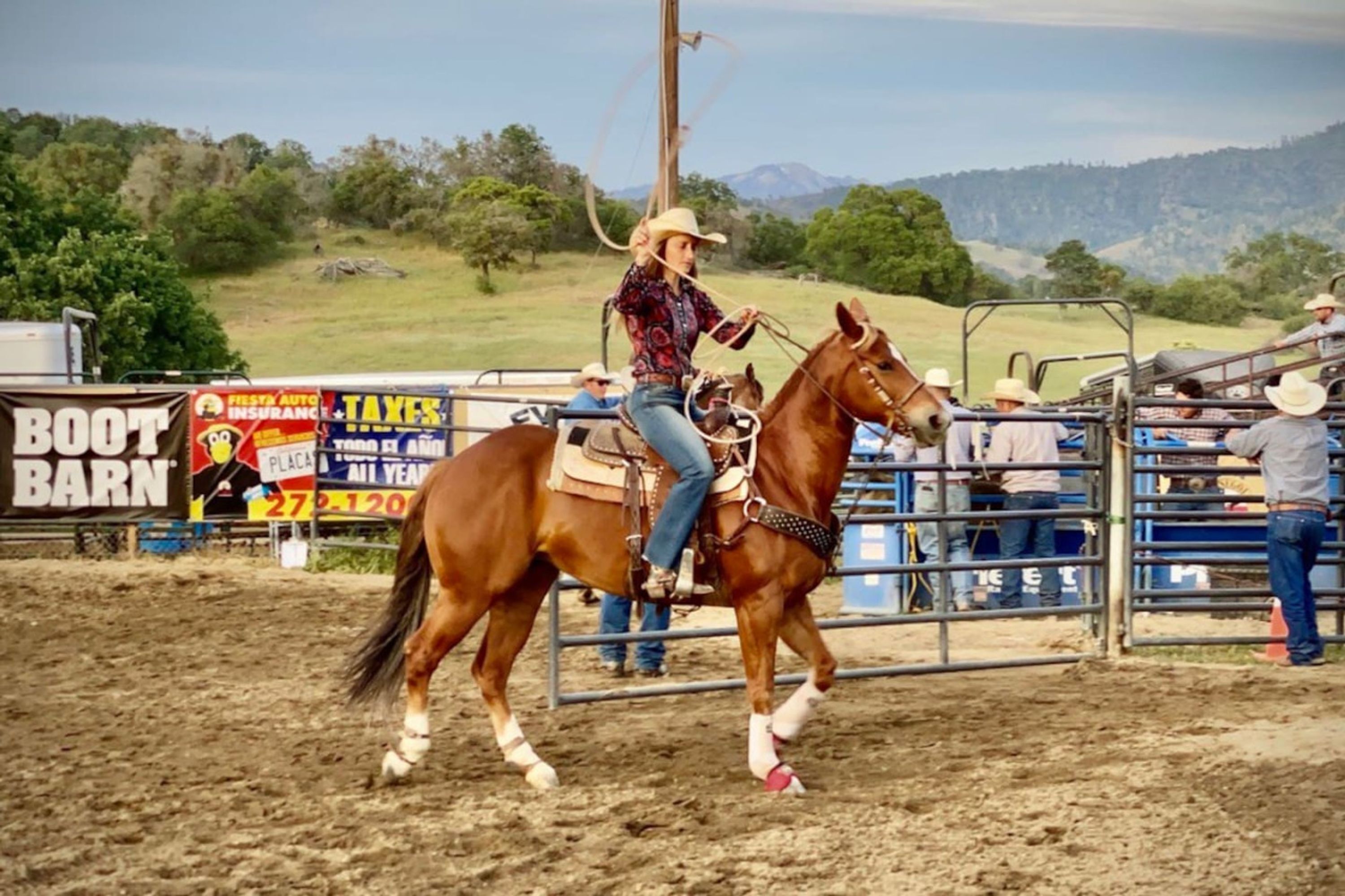 Una persona montada a caballo en una arena de tierra, rodeada por una valla.