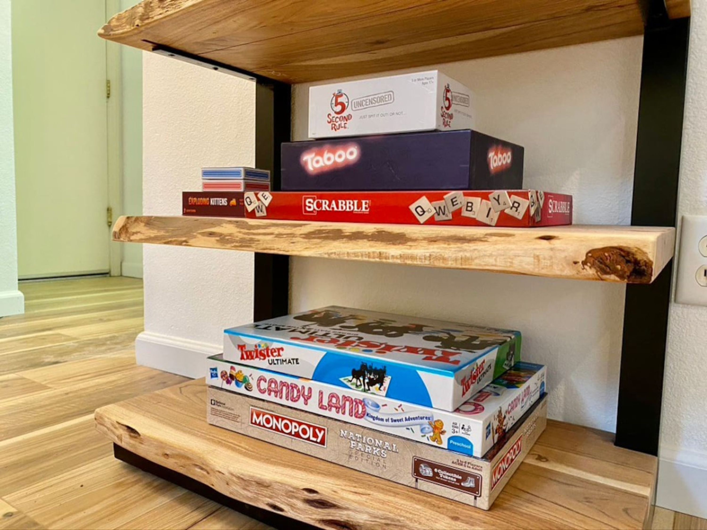 Una estantería con diversos juegos de mesa, incluyendo Scrabble, Taboo y Candy Land.