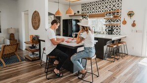 Egy modern konyha központi szigettel, függesztett lámpákkal és mintás csempeburkolattal.
