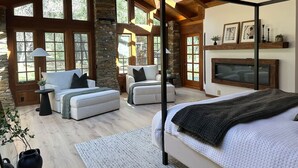 A spacious room with a large bed, two sofas, a fireplace, and large windows. - Casa Oso Estate Time Together Near Yosemite (Mariposa)