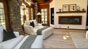 A spacious living room with a stone wall, wooden beams, and a fireplace. - Casa Oso Estate Time Together Near Yosemite (Mariposa)