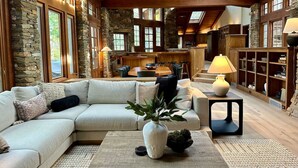 A spacious living area with a stone wall, wooden ceiling beams, and a large sofa. - Casa Oso Estate Time Together Near Yosemite (Mariposa)
