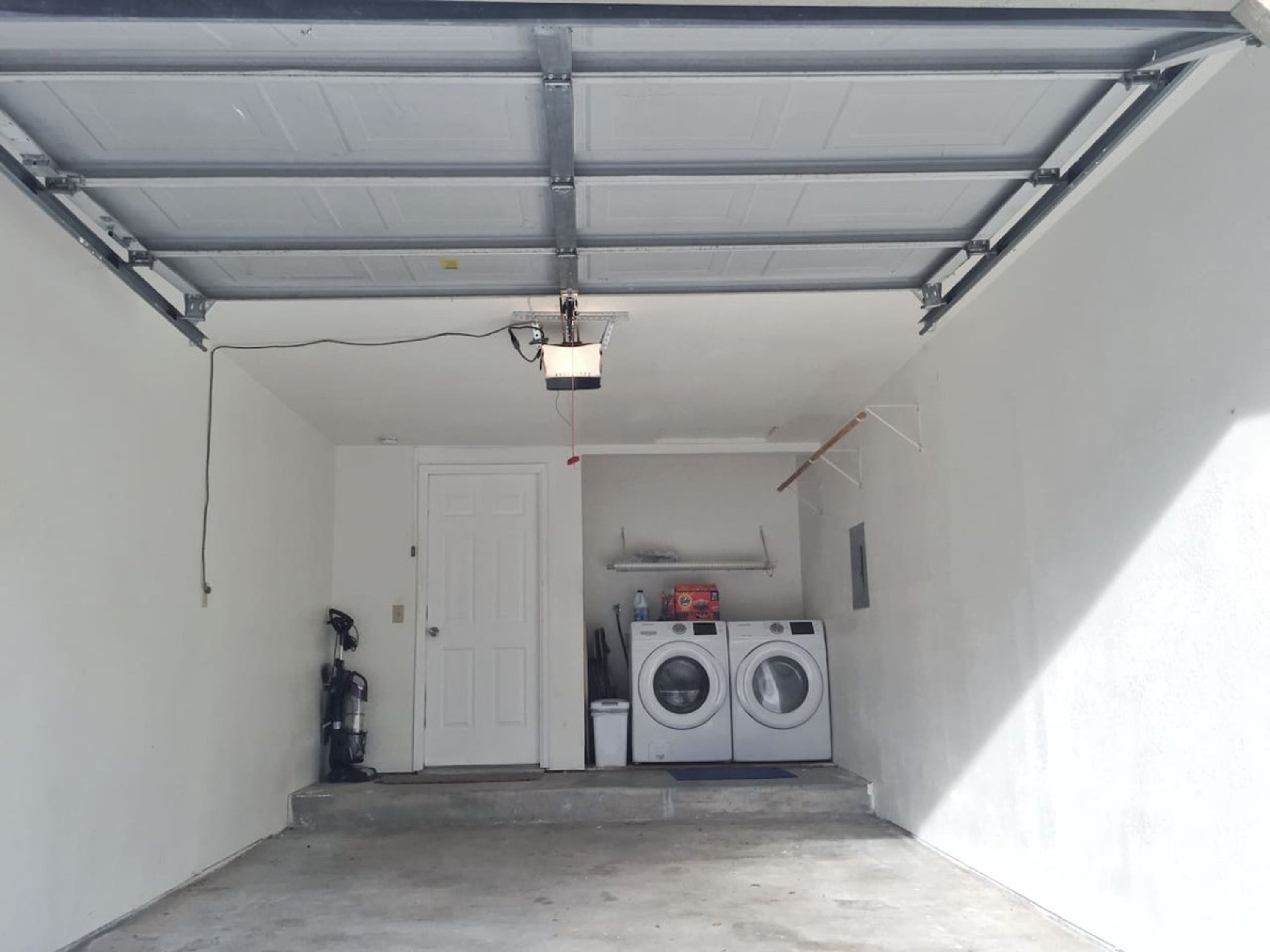 Eine Garage mit Deckenprojektor, einer Tür und einer Waschmaschine.