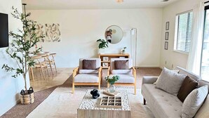 A modern living room with a sofa, two armchairs, a coffee table, a dining table with chairs, a large mirror, and a ceiling fan. - Prime Location Yosemite Adventure by Casa Oso (Oakhurst)