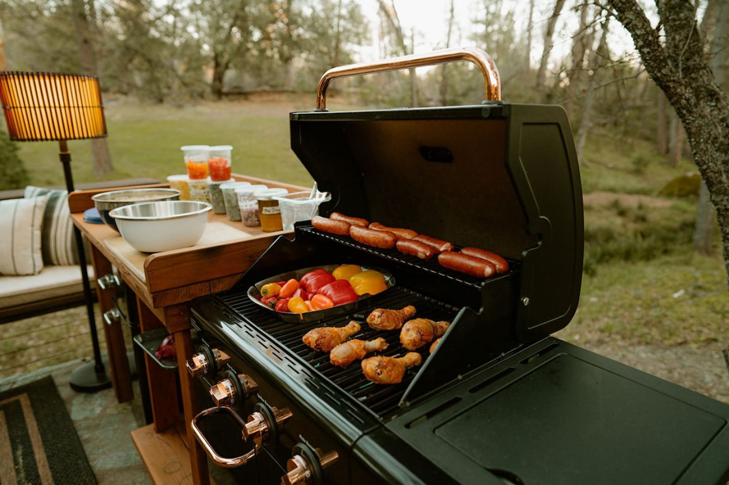 Una parrilla portátil con salchichas y verduras asándose al aire libre.