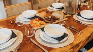 A dining table set with white plates, bowls, cutlery, and a glass of water.